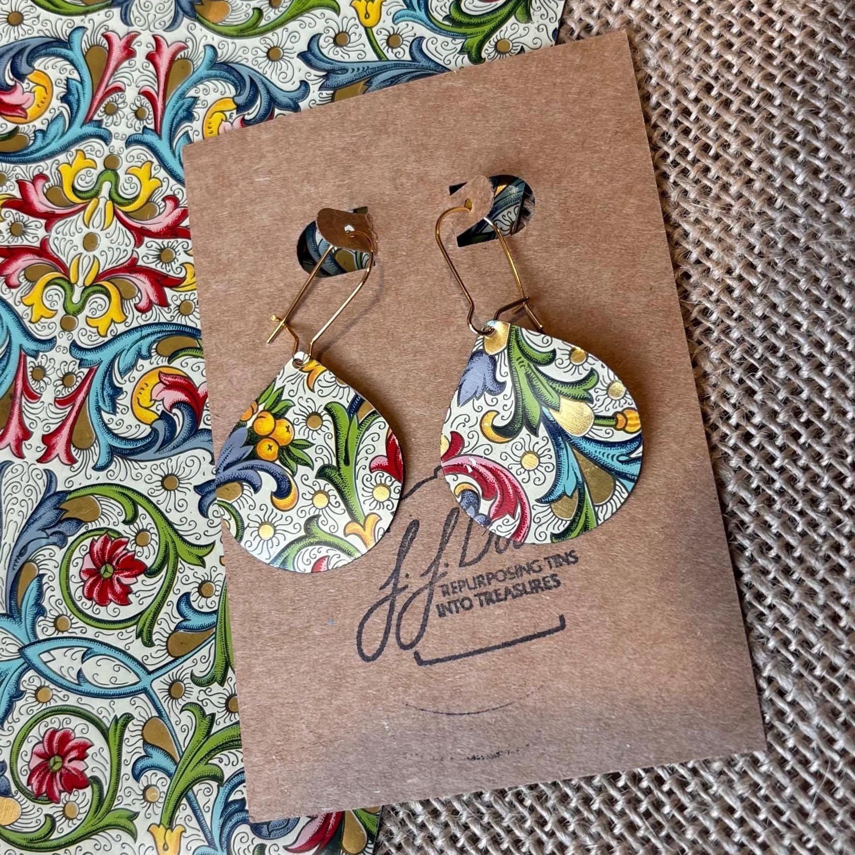 Colorful earrings on a brown card with a decorative pattern in the background
